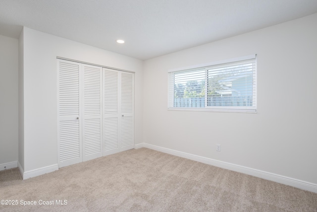 unfurnished bedroom featuring a closet and light colored carpet