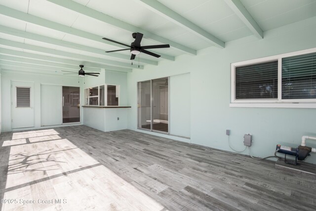 unfurnished living room with wood-type flooring, ceiling fan, and beamed ceiling