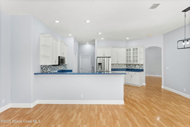 kitchen featuring light hardwood / wood-style flooring, appliances with stainless steel finishes, kitchen peninsula, pendant lighting, and white cabinets