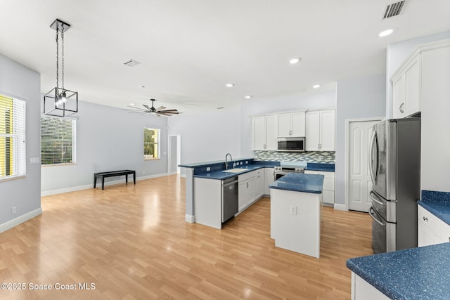 kitchen with pendant lighting, sink, appliances with stainless steel finishes, white cabinets, and kitchen peninsula