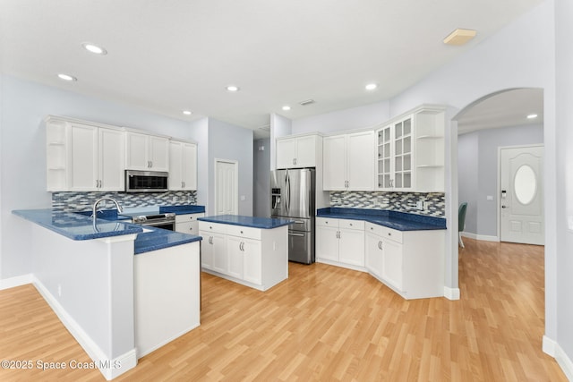 kitchen featuring white cabinetry, light hardwood / wood-style floors, kitchen peninsula, and appliances with stainless steel finishes