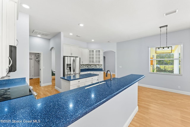 kitchen featuring pendant lighting, white cabinetry, stainless steel fridge, backsplash, and light hardwood / wood-style floors