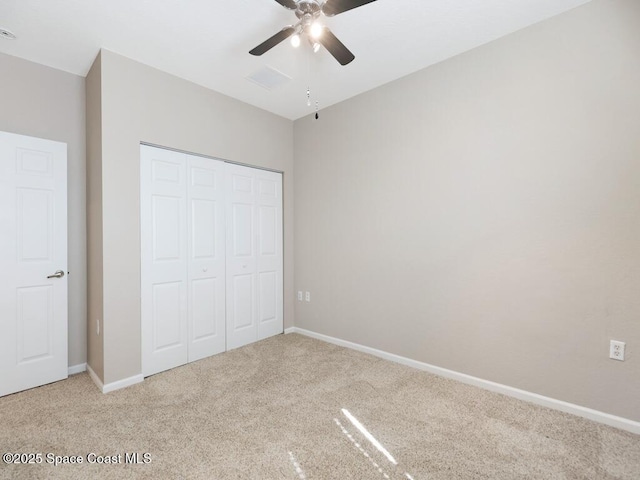 unfurnished bedroom featuring ceiling fan, light colored carpet, and a closet