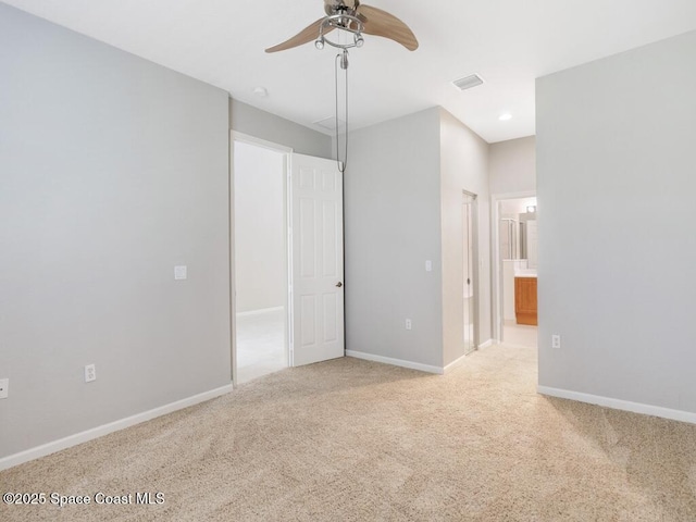 unfurnished bedroom featuring ensuite bathroom, light colored carpet, and ceiling fan