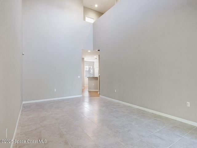 tiled spare room featuring a towering ceiling