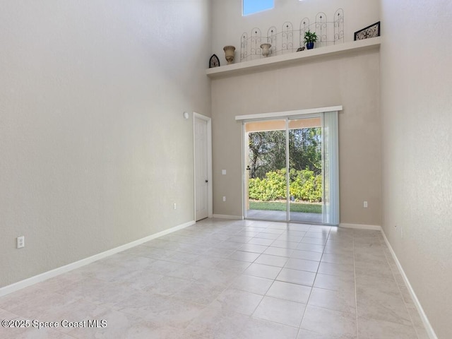 unfurnished room with light tile patterned flooring and a high ceiling