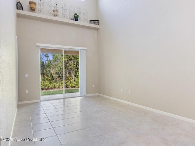 spare room with light tile patterned floors and a high ceiling