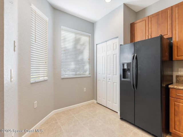 kitchen with light tile patterned flooring, plenty of natural light, and black fridge with ice dispenser