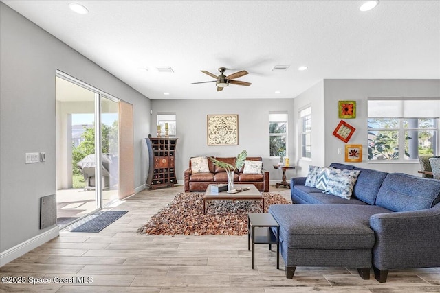 living room with a textured ceiling, ceiling fan, and light hardwood / wood-style flooring