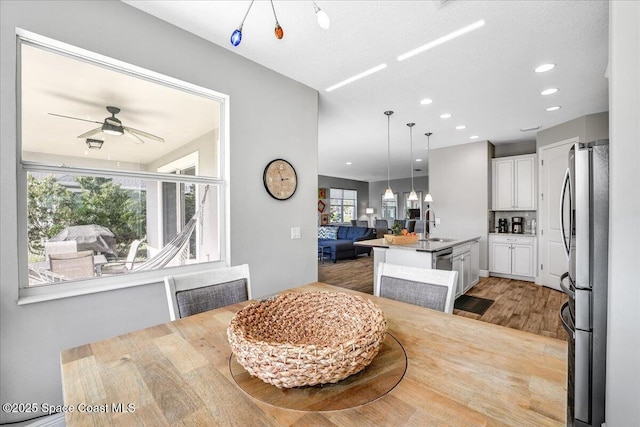 dining room featuring ceiling fan, sink, and light wood-type flooring