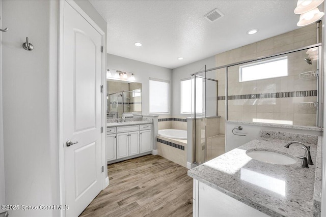 bathroom featuring vanity, hardwood / wood-style flooring, independent shower and bath, and a textured ceiling