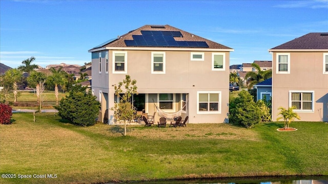 back of house with a yard and solar panels