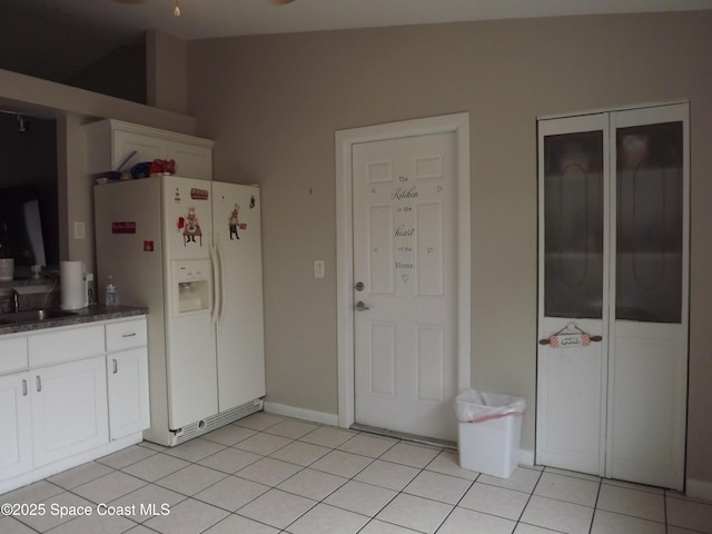 kitchen featuring light tile patterned flooring, white cabinets, sink, and white fridge with ice dispenser