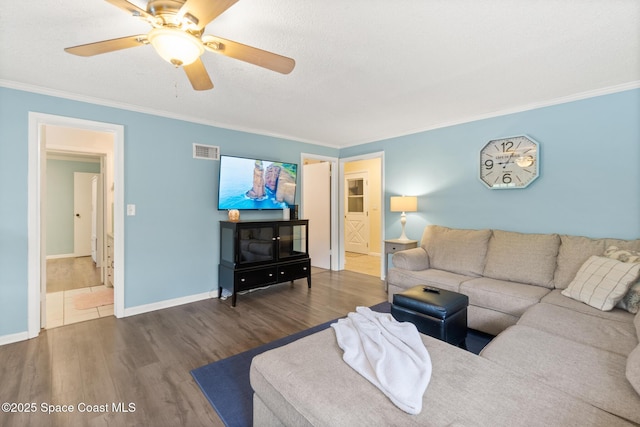 living area featuring baseboards, visible vents, dark wood-style floors, ceiling fan, and ornamental molding