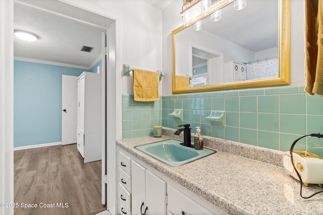 full bath with visible vents, wood finished floors, crown molding, vanity, and tile walls