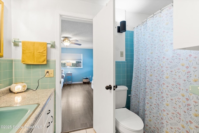 bathroom with tasteful backsplash, toilet, a ceiling fan, vanity, and a textured ceiling