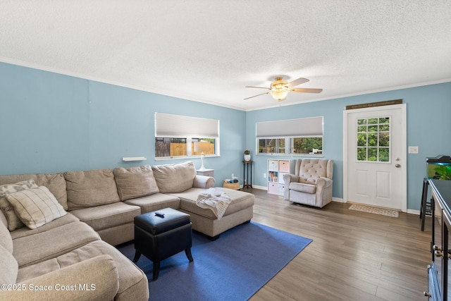 living area featuring ornamental molding, a textured ceiling, baseboards, and wood finished floors