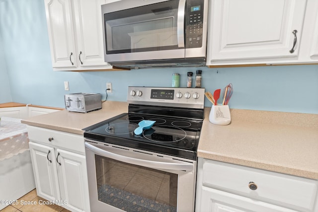 kitchen with stainless steel appliances, light countertops, and white cabinetry