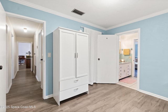 unfurnished bedroom with ornamental molding, a closet, visible vents, and light wood-style flooring