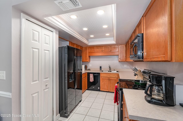 kitchen with sink, light tile patterned floors, black appliances, and a raised ceiling