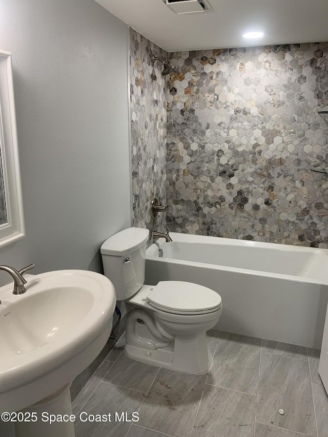 full bathroom with tiled shower / bath combo, sink, and toilet