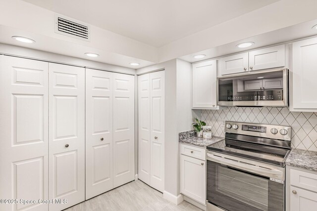 kitchen with white cabinetry, tasteful backsplash, appliances with stainless steel finishes, and light stone counters