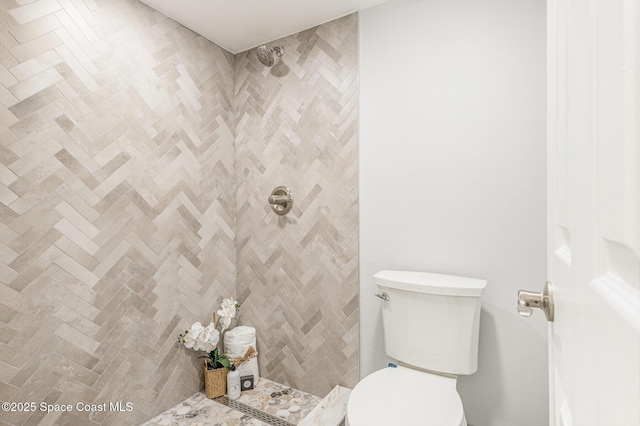 bathroom featuring tiled shower and toilet