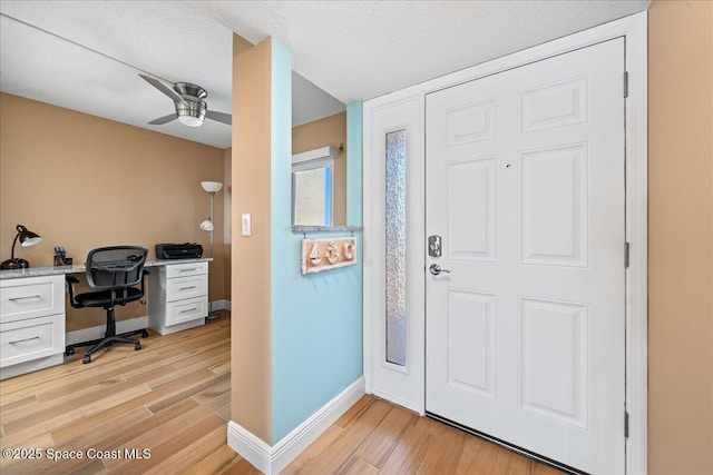 entrance foyer featuring a textured ceiling, built in desk, ceiling fan, and light wood-type flooring