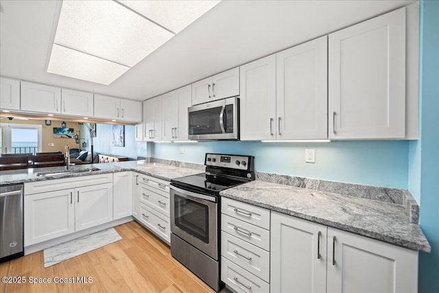 kitchen with white cabinetry, sink, light hardwood / wood-style floors, and appliances with stainless steel finishes