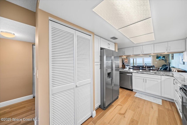 kitchen featuring appliances with stainless steel finishes, sink, white cabinets, and light hardwood / wood-style floors