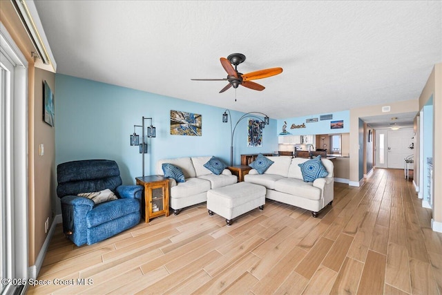 living room featuring a textured ceiling, ceiling fan, and light hardwood / wood-style flooring