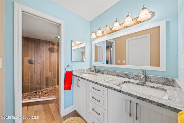 bathroom with tiled shower and vanity