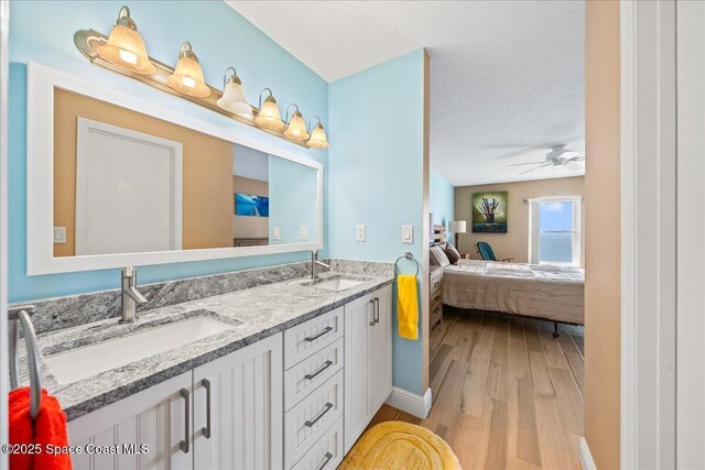 bathroom with hardwood / wood-style flooring, vanity, ceiling fan, and a textured ceiling