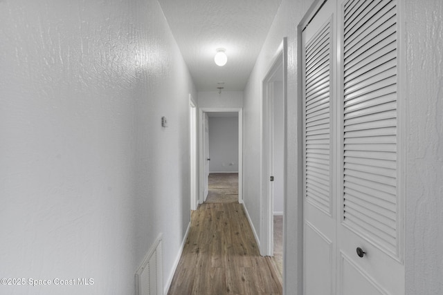 hall with hardwood / wood-style flooring and a textured ceiling