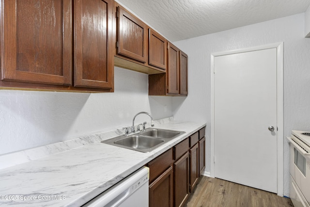 kitchen featuring hardwood / wood-style flooring, white appliances, sink, and a textured ceiling