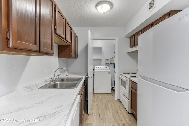 kitchen featuring washer / dryer, sink, light hardwood / wood-style flooring, a textured ceiling, and white appliances