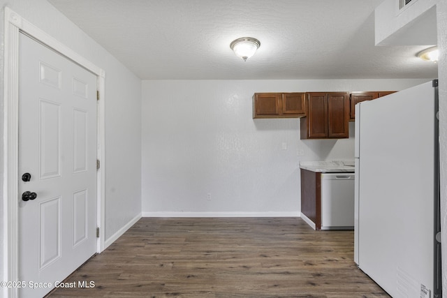 kitchen featuring dark hardwood / wood-style flooring, dishwasher, white fridge, and a textured ceiling