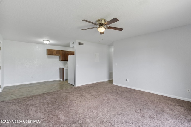 unfurnished living room featuring ceiling fan, dark carpet, and a textured ceiling