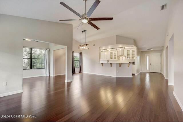 unfurnished living room featuring dark wood-type flooring, high vaulted ceiling, and ceiling fan