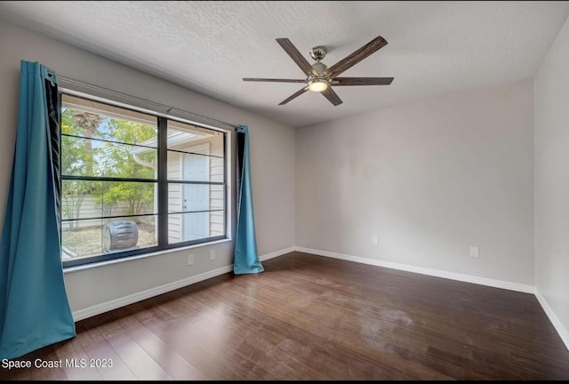 empty room with ceiling fan, dark hardwood / wood-style floors, and a textured ceiling