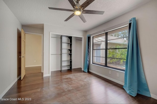 unfurnished bedroom with ceiling fan, dark hardwood / wood-style flooring, a closet, and a textured ceiling