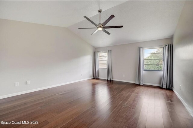 unfurnished room featuring lofted ceiling, dark wood-type flooring, and a wealth of natural light