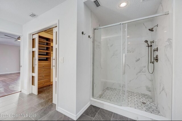 bathroom with ceiling fan, a textured ceiling, and walk in shower