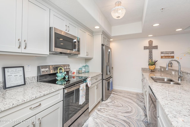 kitchen featuring sink, light stone countertops, white cabinets, and appliances with stainless steel finishes