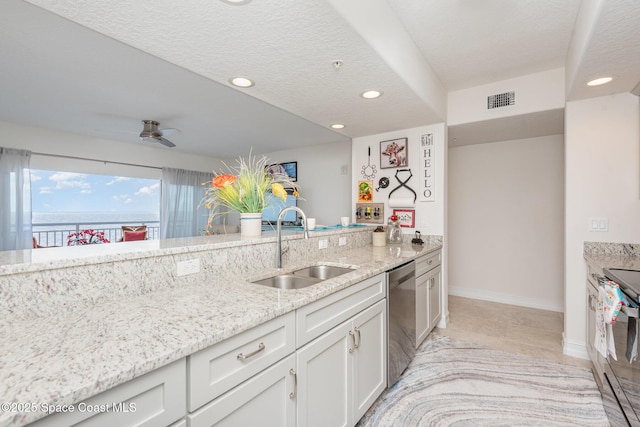 kitchen with sink, ceiling fan, appliances with stainless steel finishes, white cabinetry, and light stone counters