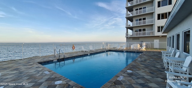 view of pool with a patio and a water view