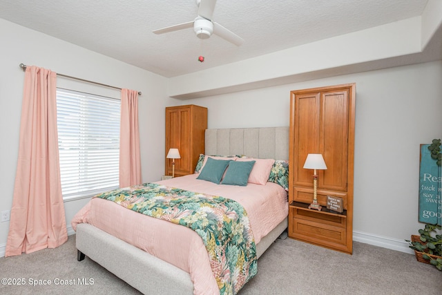 bedroom with ceiling fan, light carpet, and a textured ceiling