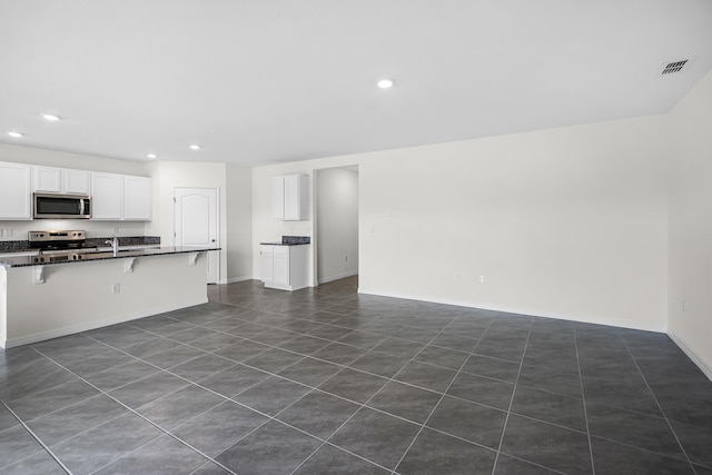 kitchen featuring white cabinetry, sink, stainless steel appliances, and a kitchen breakfast bar