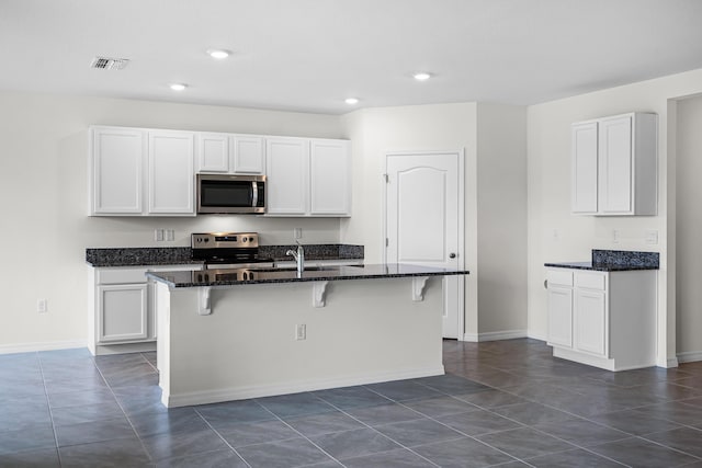 kitchen with white cabinetry, a kitchen bar, stainless steel appliances, and a center island with sink