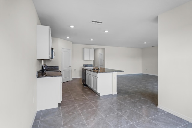 kitchen featuring white cabinetry, sink, dark tile patterned floors, stainless steel appliances, and a center island with sink